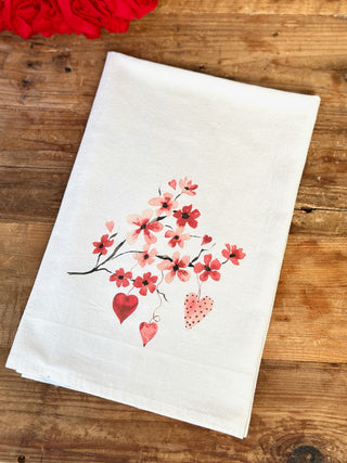 a festive valentine tea towel with pink and red hearts and cherry blossom flowers