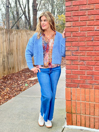 a fuzzy blue cropped cardigan sweater for layered warmth worn over a vibrant blouse