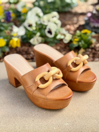 a pair of tan camel leather clog sandals with a chic wooden chain link