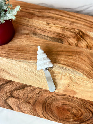 a silver holiday cheese spreader with a white embossed christmas tree