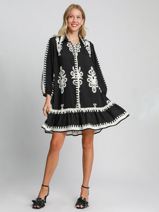 black and white border print collared mini dress with button down design worn with black heels 