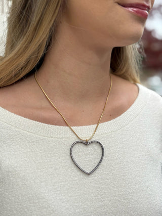 a gold snake chain necklace with an open gunmetal heart and rhinestones