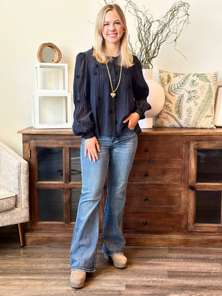 a sheer black long sleeve button up top with velvety floral details worn with light denim jeans