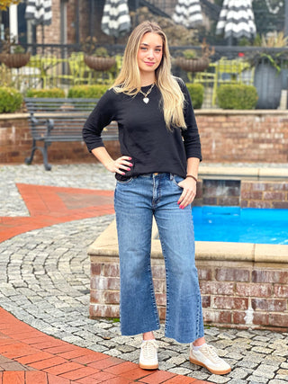 a basic black crew neck shirt with three quarter sleeves worn with light blue jeans