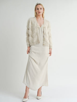 long sleeve fuzzy and feathered cream sweater cardigan worn on top of maxi silk dress