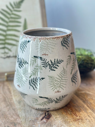 a white and cream ceramic pot with a fresh green fern pattern