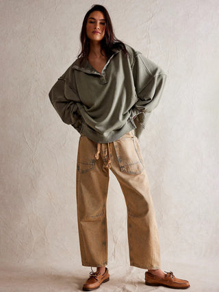 free people green oversized henley sweatshirt with a collared neckline and snap button closures with shoulder sleeves paired with tan pants 