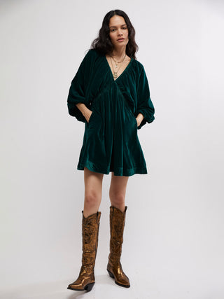 a shimmering emerald green velvet mini dress with a v neck and relaxed fit worn with cowgirl boots