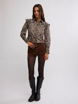 a fun black floral long sleeve blouse with shoulder accents and a button front worn with brown shorts