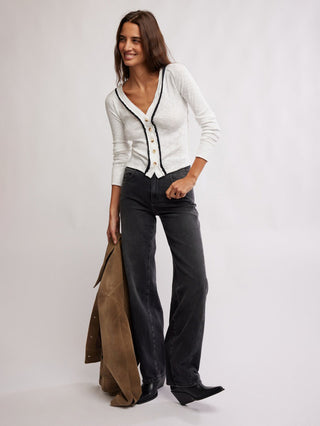 a classic yet flirty white button down v neck cardigan with a black trim worn with black jeans