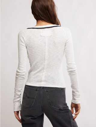 a classic yet flirty white button down v neck cardigan with a black trim worn with black jeans