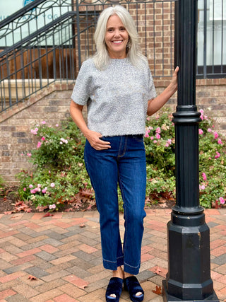 a glimmering silver short sleeve sweater top with metallic threads worn with dark blue jeans