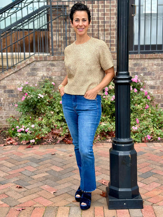 a glimmering gold short sleeve sweater top with metallic threads worn with blue jeans