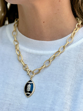 a chunky gold chain necklace with a black football pendant and front lobster clasp