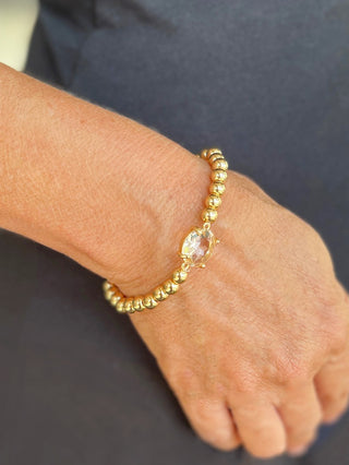 shimmering gold beaded bracelet with clear stone centerpiece