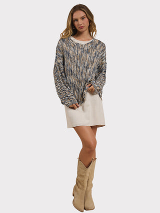 a comfy and relaxed multi colored navy v neck sweater with long sleeves worn with a beige skirt