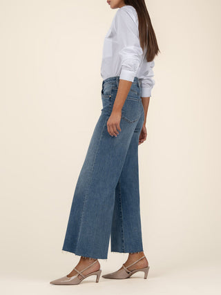 a pair of high rise wide leg denim jeans with a raw hem worn with a white blouse