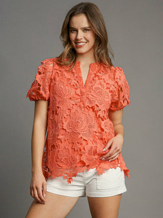 a lacy coral orange top with puff sleeves and a split neckline