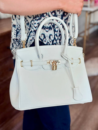 a white faux leather handbag with gold accents