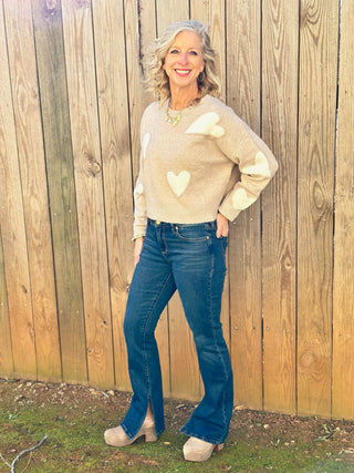 a cute taupe lover sweater with bold white hearts worn with blue jeans and taupe heels