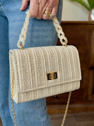 a small chic ivory cream straw mini bag with a marbled chain link handle and gold clasp