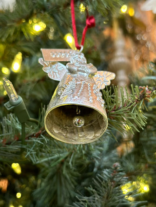 a silver angel ornament with a bell inside