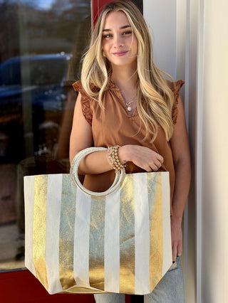 a large gold and white striped vacation tote bag with a circular handle