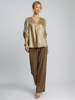 a classy oversized gold metallic v neck blouse that shimmers paired with brown pants