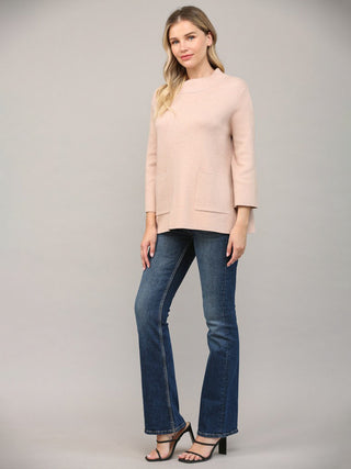 a simple rose gold mock neck sweater with front pockets worn with dark blue jeans