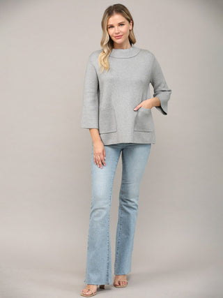 a simple silver mock neck sweater with three quarter sleeves worn with light blue jeans