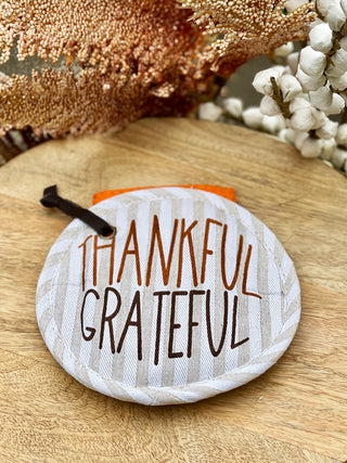 a festive pot holder set with thankful grateful on front and an orange autumnal dish towel