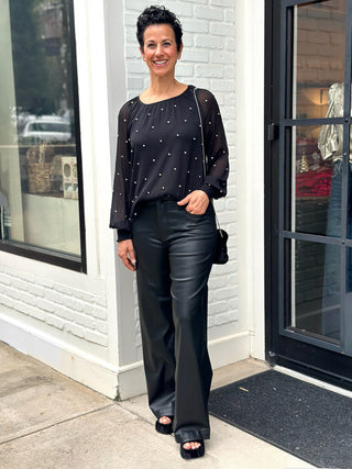 a classy black sheer long sleeve blouse with silver rhinestones and elastic cuffs worn with black pants