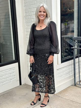 a playful black mixed texture sweater top with sheer sleeves worn with a black sequin skirt