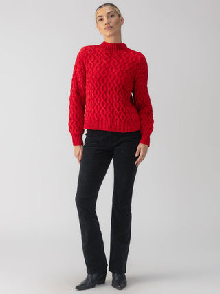 a cozy red mock neck cable knit sweater for the holidays worn with black pants