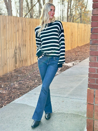 a soft chic cropped black and white striped sweater worn with dark blue jeans and black boots