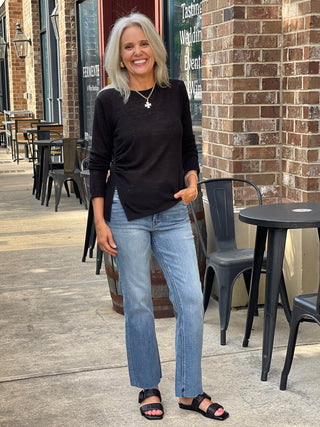 a breezy long sleeve crewneck black top with a sheer design and side slit worn with jeans