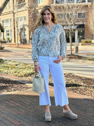 a green and white paisley long sleeve blouse paired with wide leg white jeans