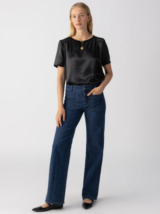 a classic yet flattering black satin short sleeve tee worn with dark blue jeans