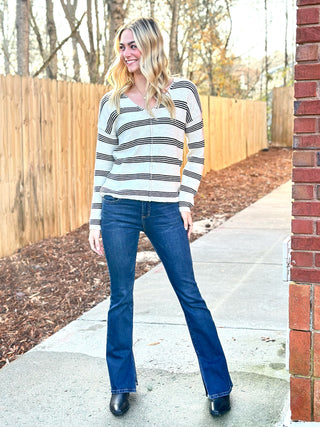 a casual light oak cream and black striped v neck sweater top paired with blue jeans