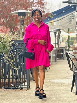 a fun magenta pink satin button down dress with long sleeves worn with velvety black heels