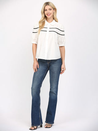 an off white button up blouse with black stripes and three quarter puff sleeves worn with dark denim