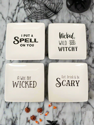 a collection of off white stoneware serving plates with spooky sentiments in black type perfect for halloween decor