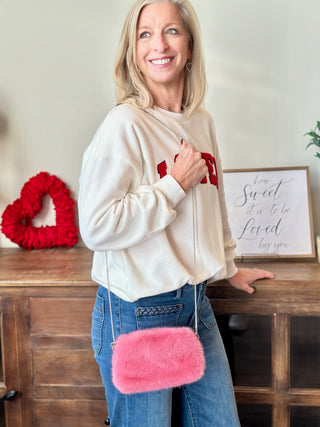 a chic fuzzy pink fur crossbody clutch bag worn with a lover sweatshirt