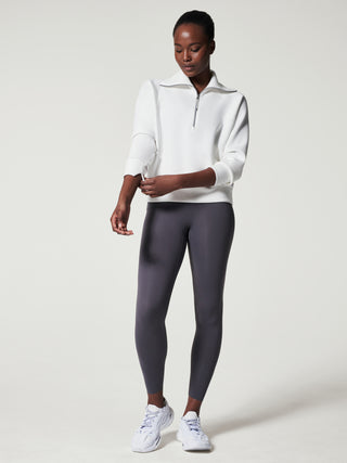 a soft half zip white pullover with a refined collar worn with gray leggings