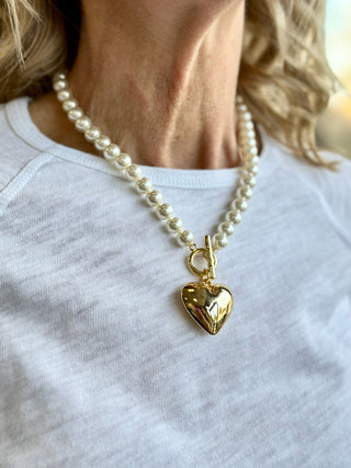 A chunky gold and pearl beaded necklace with a sweet heart pendant and front clasp