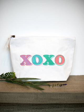 a white cosmetics bag with xoxo written in teal purple and red