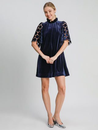 a soft sophisticated navy velvet mini dress with a dotted lace sleeve paired with metallic shoes