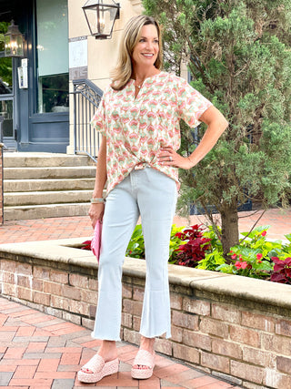 relaxed fit cream v neck top with a unique watermelon colored floral design worn with light blue pants