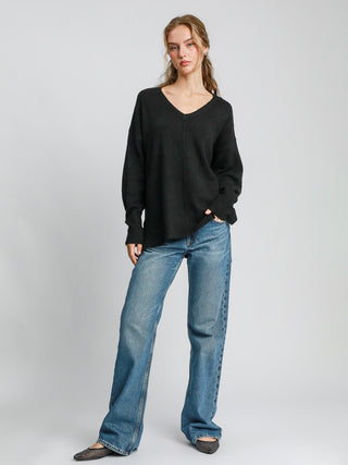 a relaxed fit black v neck knitted sweater with cut edge details worn with blue jeans