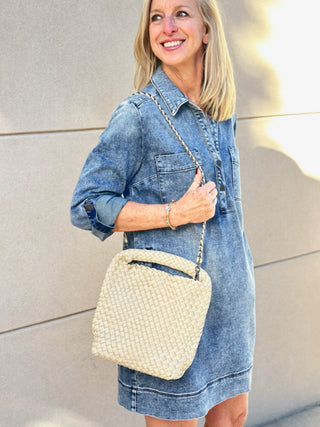 a creamy beige woven hobo handbag worn with a denim dress